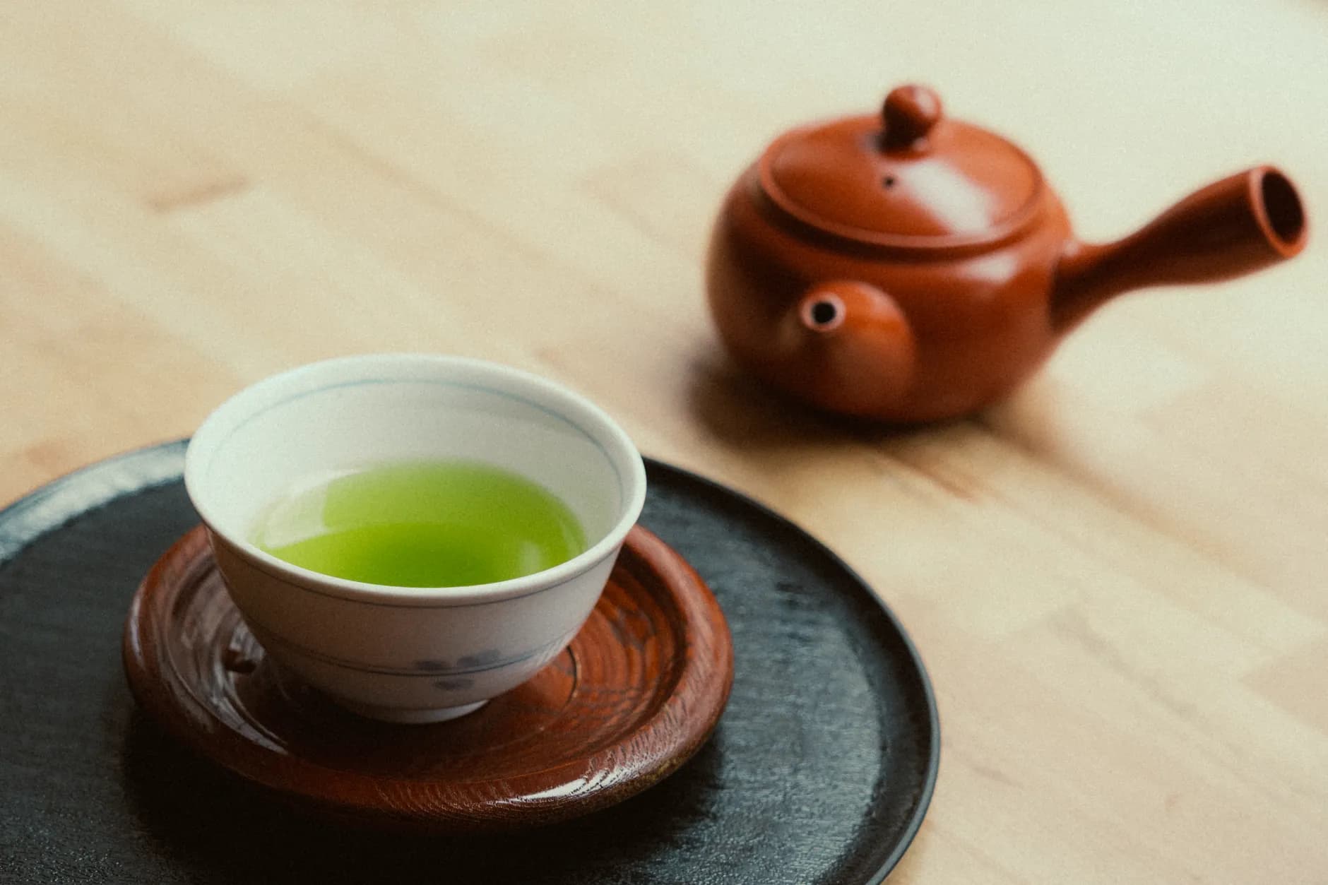 Cup of green tea with fresh tea leaves on a bright surface