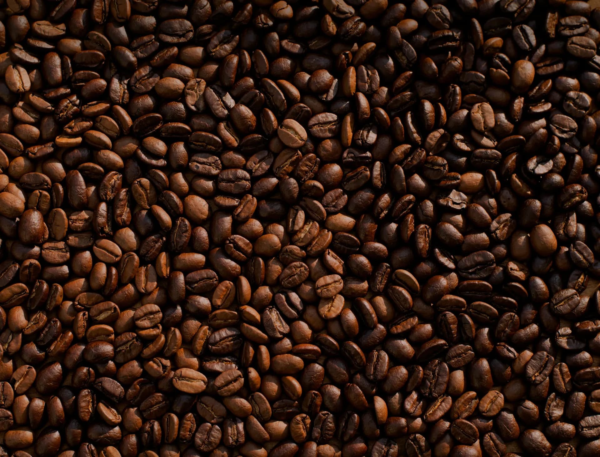 Coffee beans roasting in a drum roaster with warm amber light