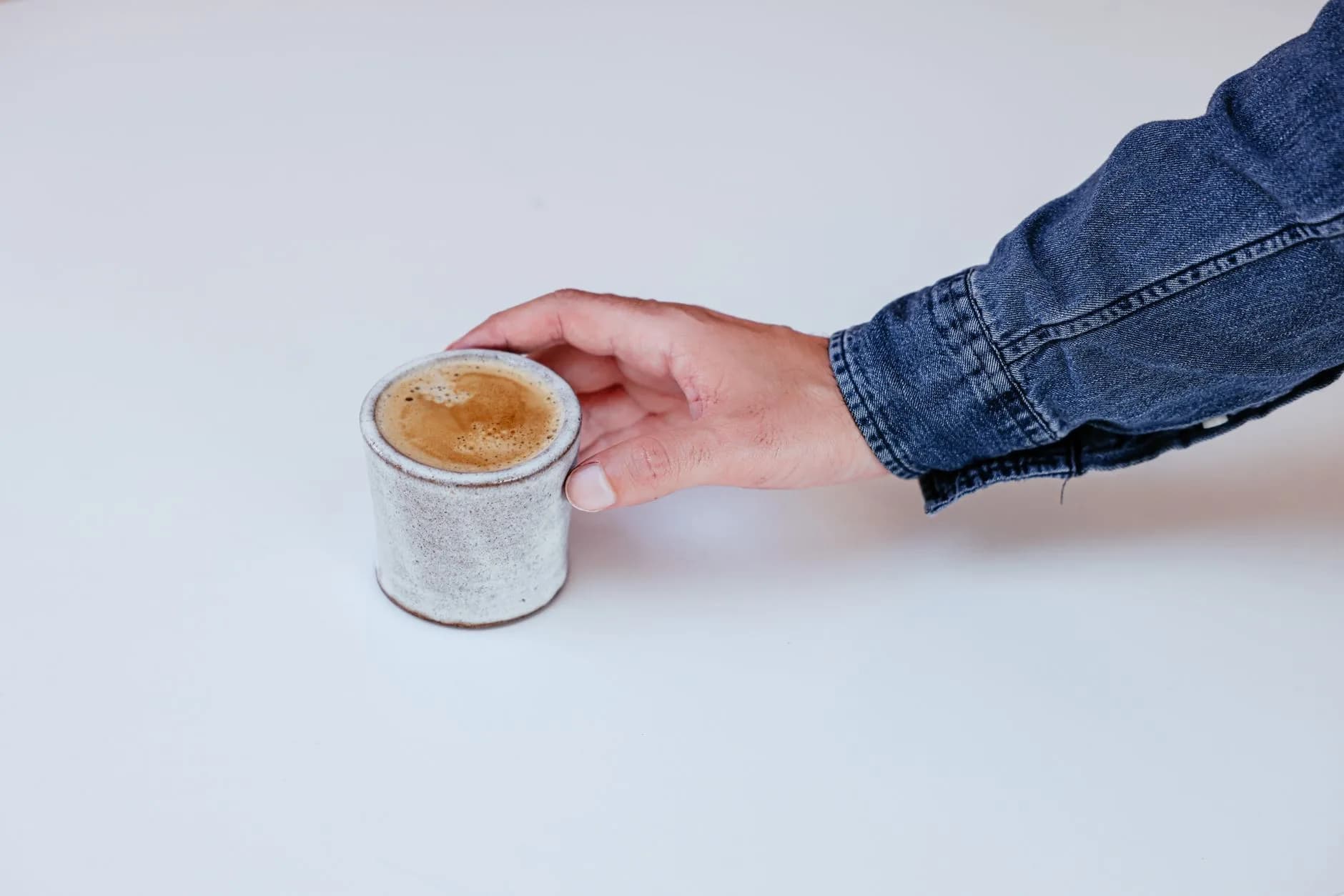 Espresso cup on a saucer beside a coffee grinder